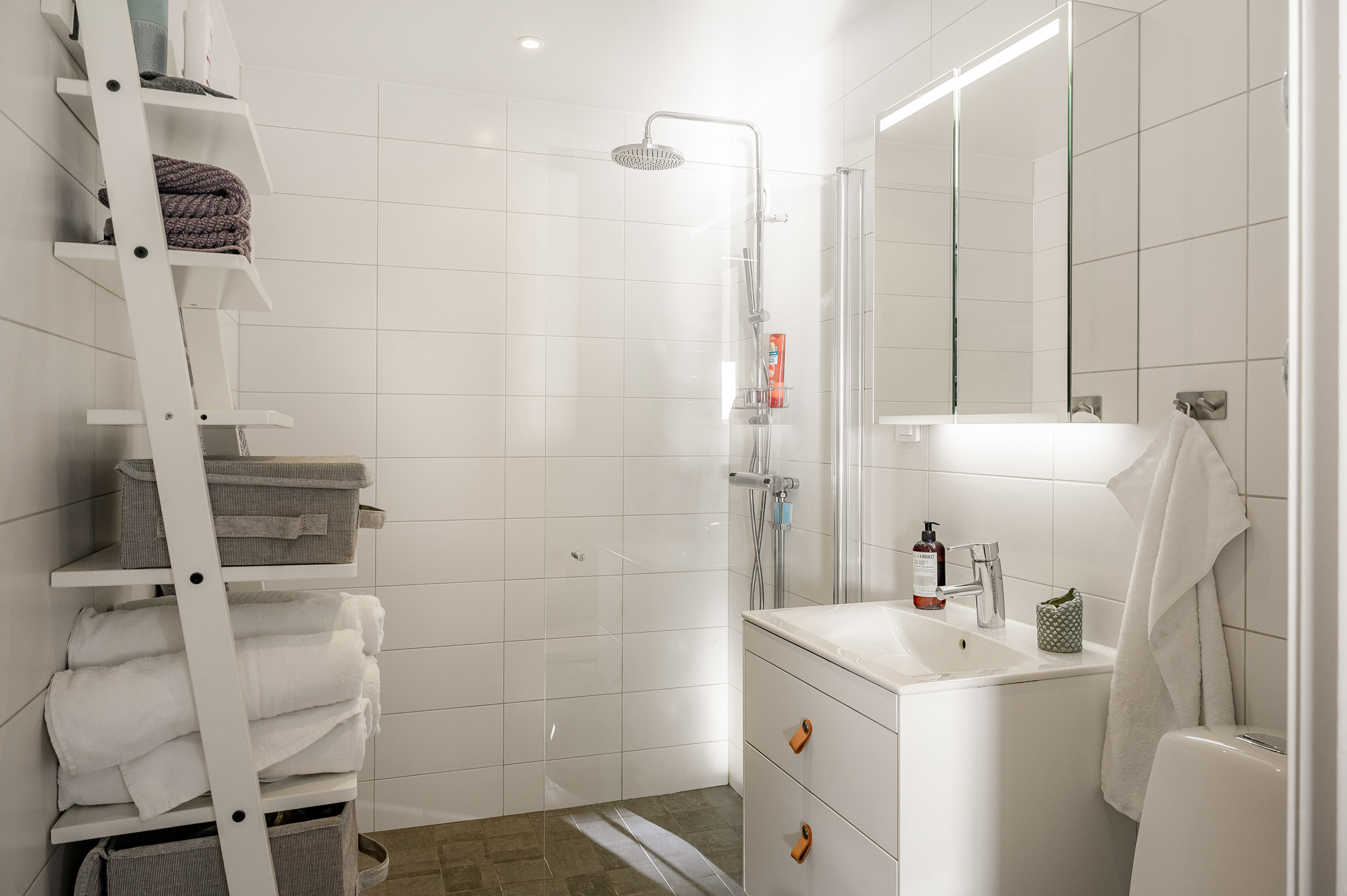 Smakfullt renoverat badrum med kakel och klinker i ljusa toner.