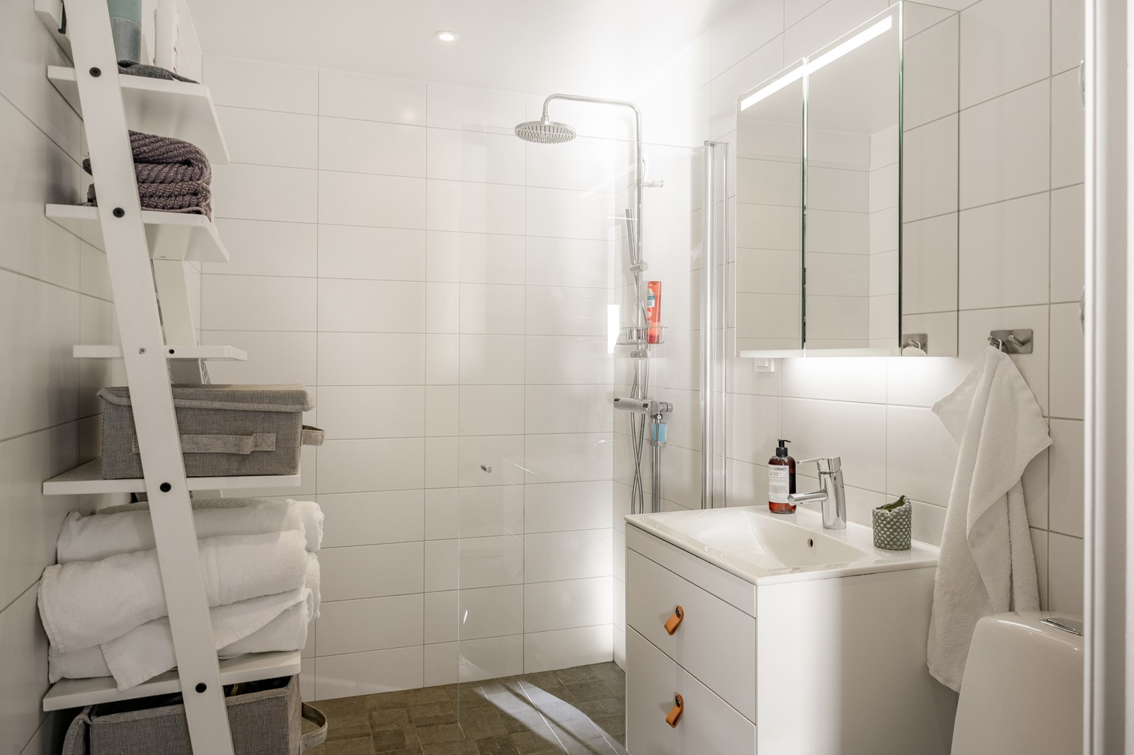 Smakfullt renoverat badrum med kakel och klinker i ljusa toner.