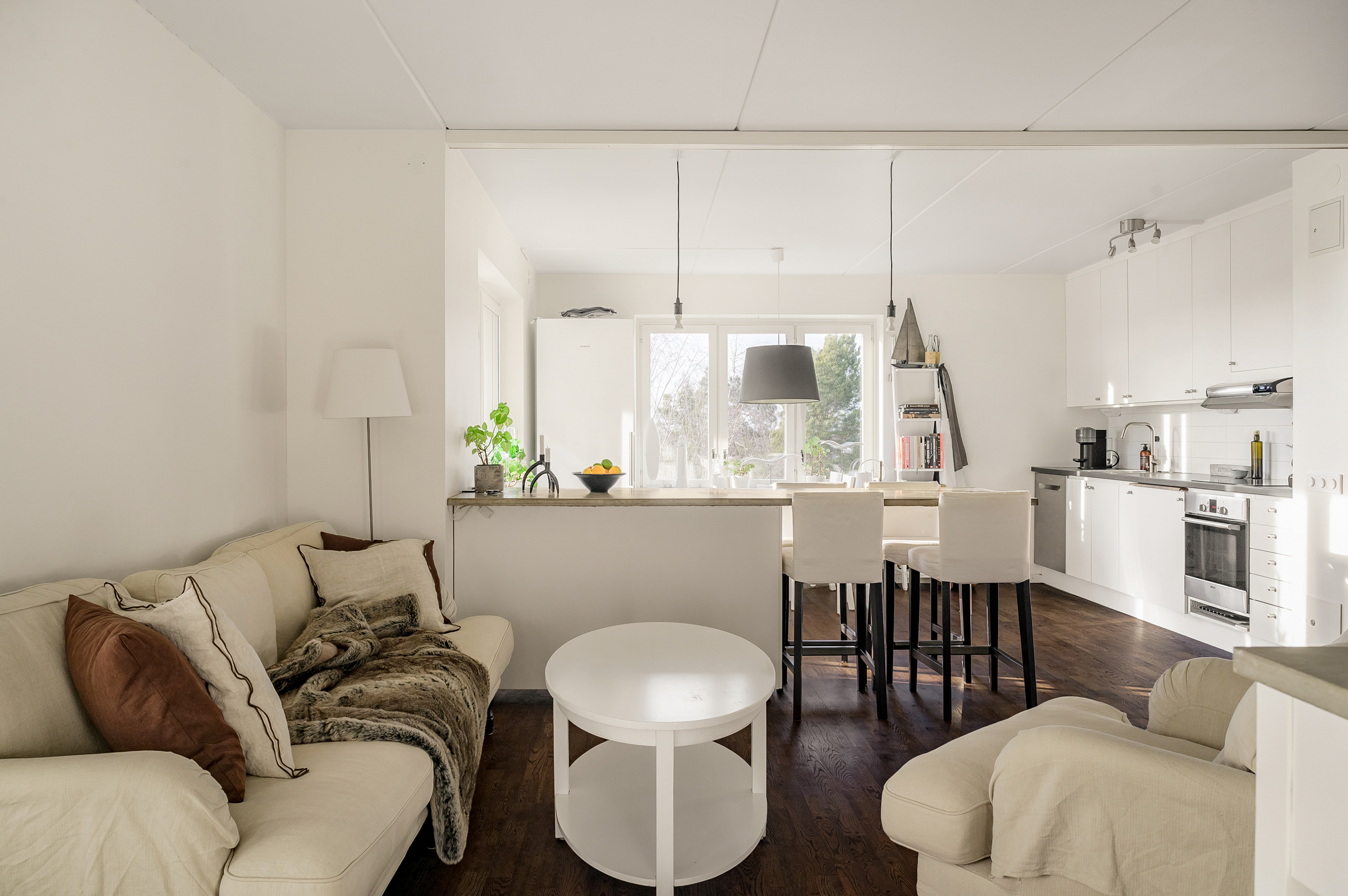 Vardagsrum med fint ljusinsläpp via köket i väster.