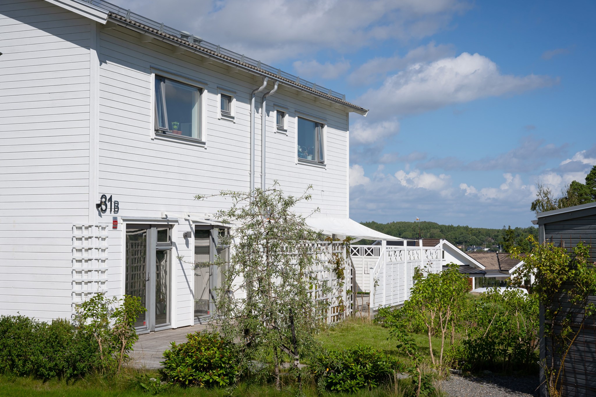 I nära anslutning till huset finns parkering med laddstolpe för elbil - höger i bild skymtar husets externa förråd