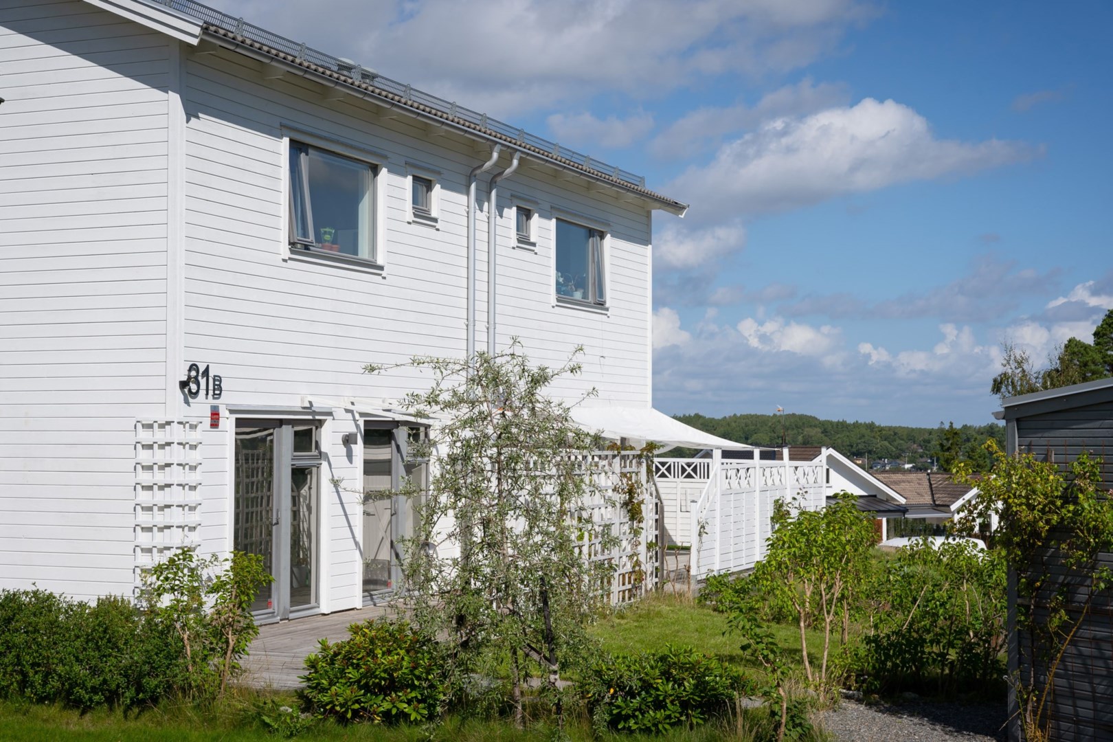 I nära anslutning till huset finns parkering med laddstolpe för elbil - höger i bild skymtar husets externa förråd