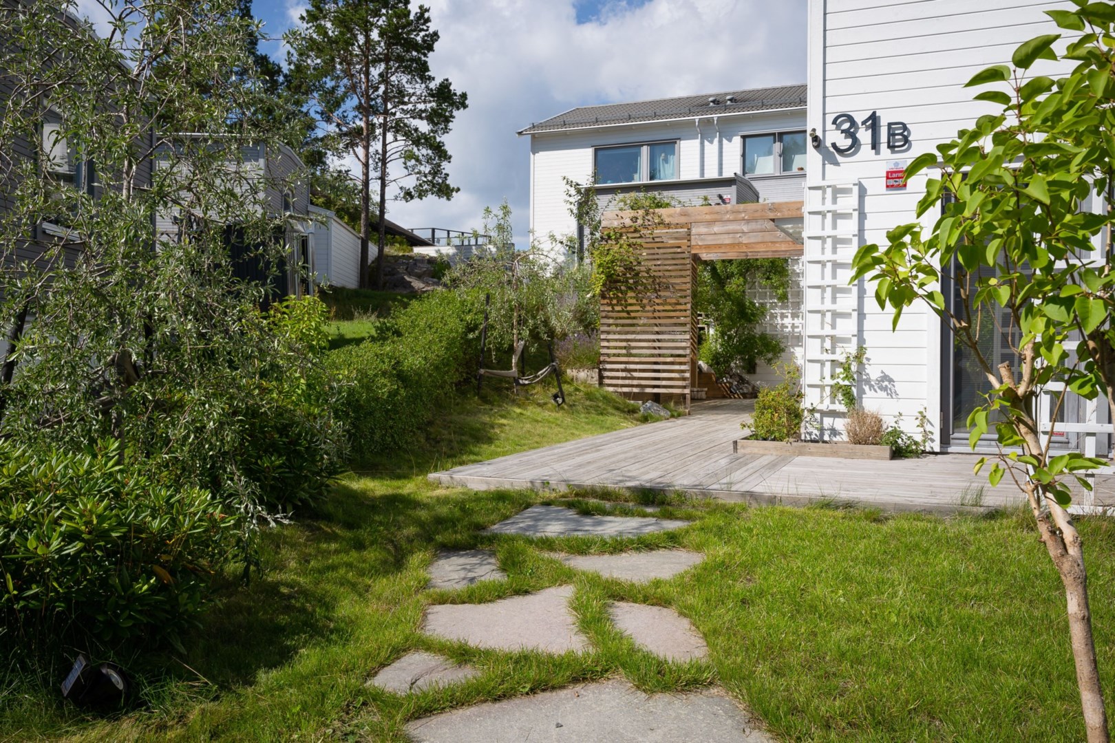 Husets entré med uppvuxen grönska som avskiljare i söder