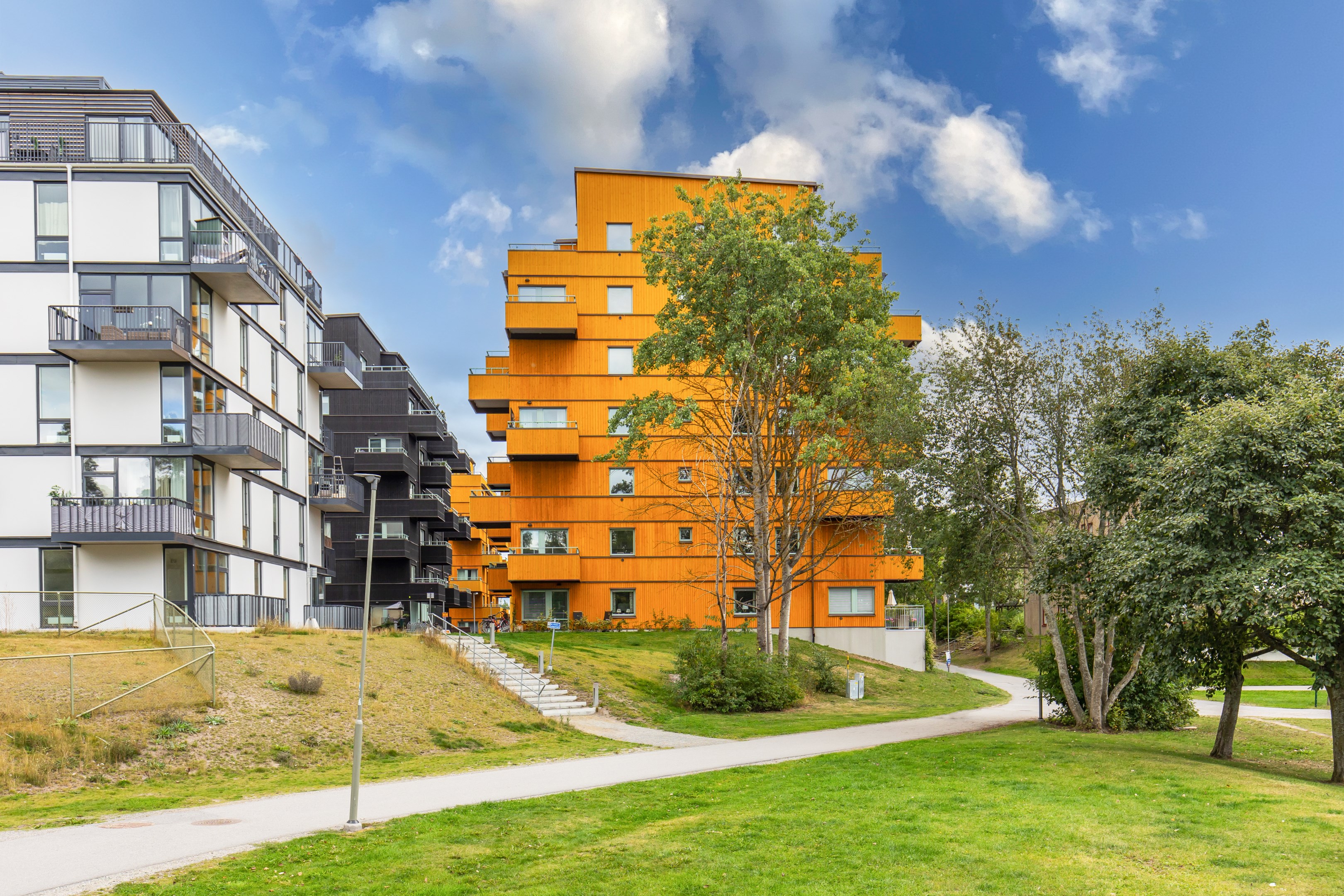 Huset i vinkel från parken i väster - balkongen skymtar i lövverket.