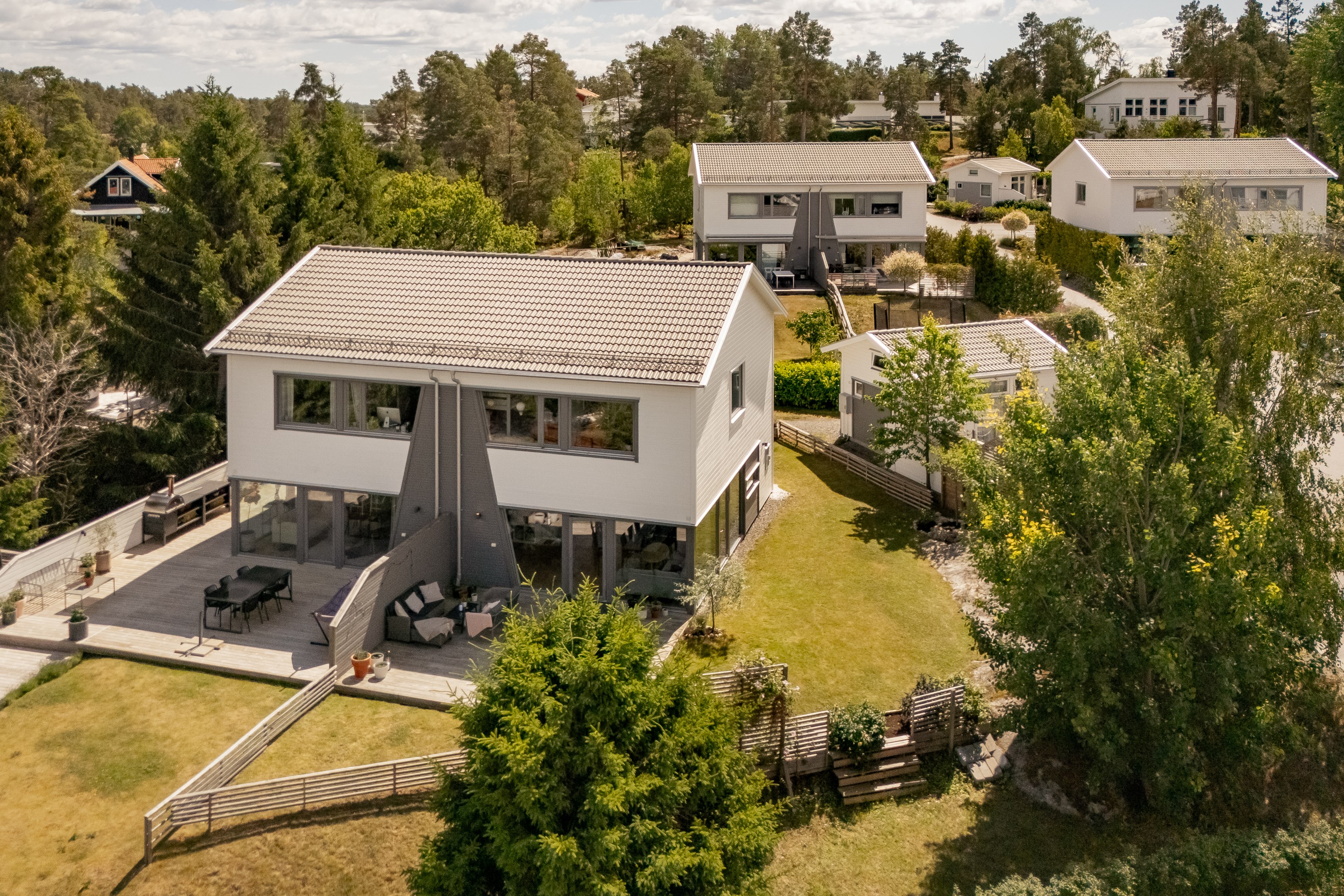 Hus och trädgård i vinkel från sjösidan i väster.