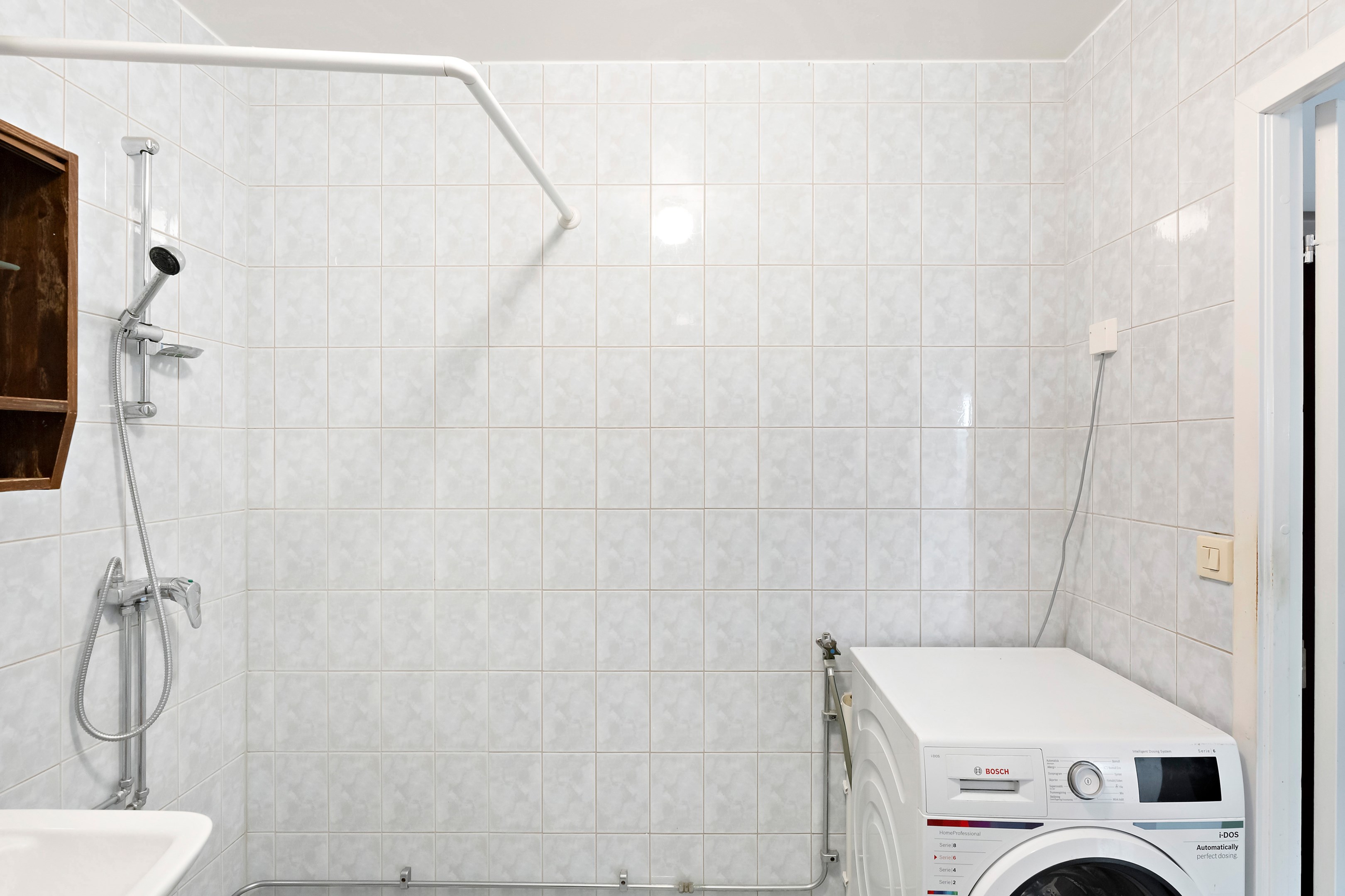 Luftigt badrum med plats för dusch, tvättmaskin och torkskåp.