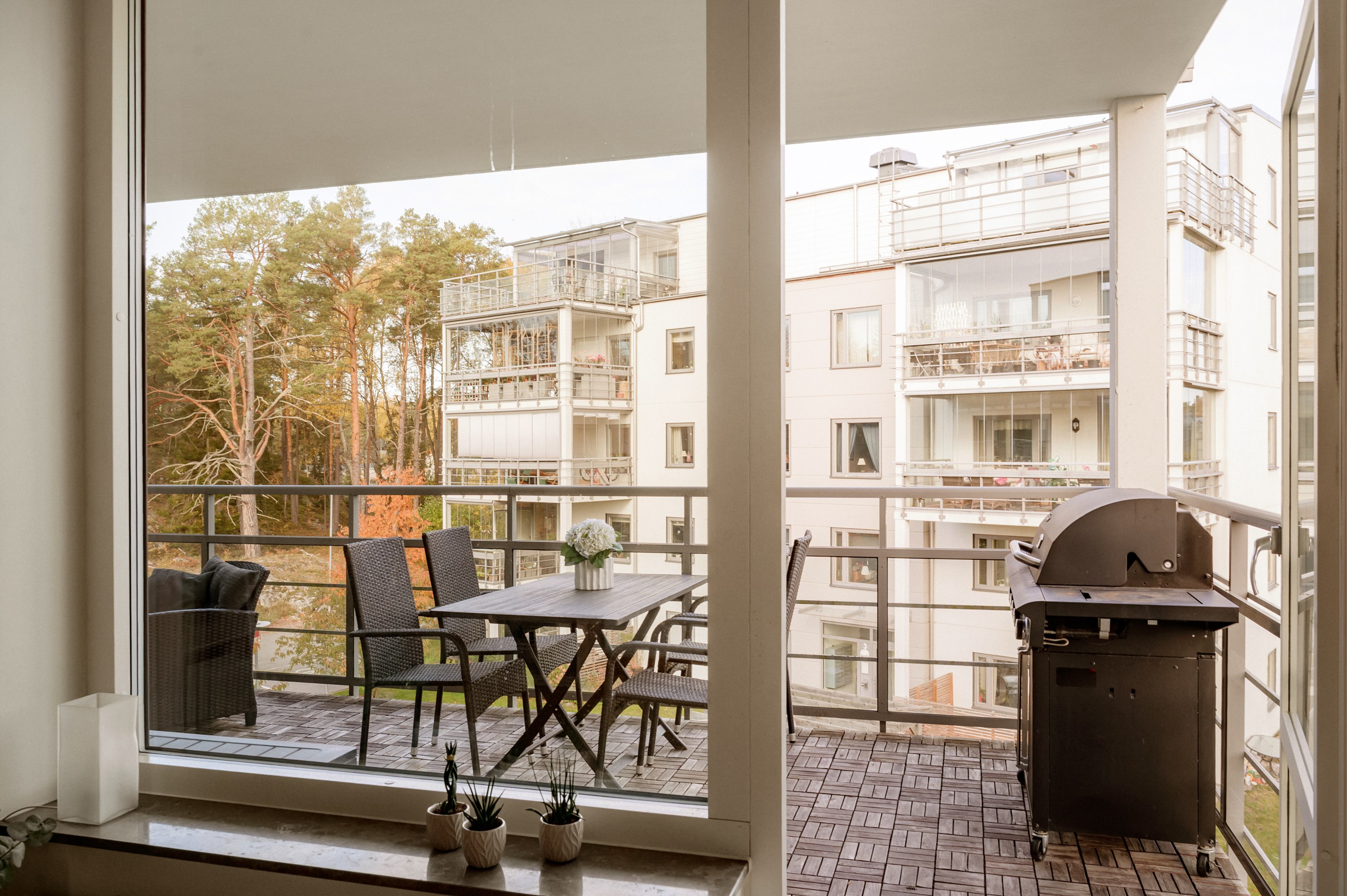 Balkongen rymmer grill, matgrupp och loungemöbler.
