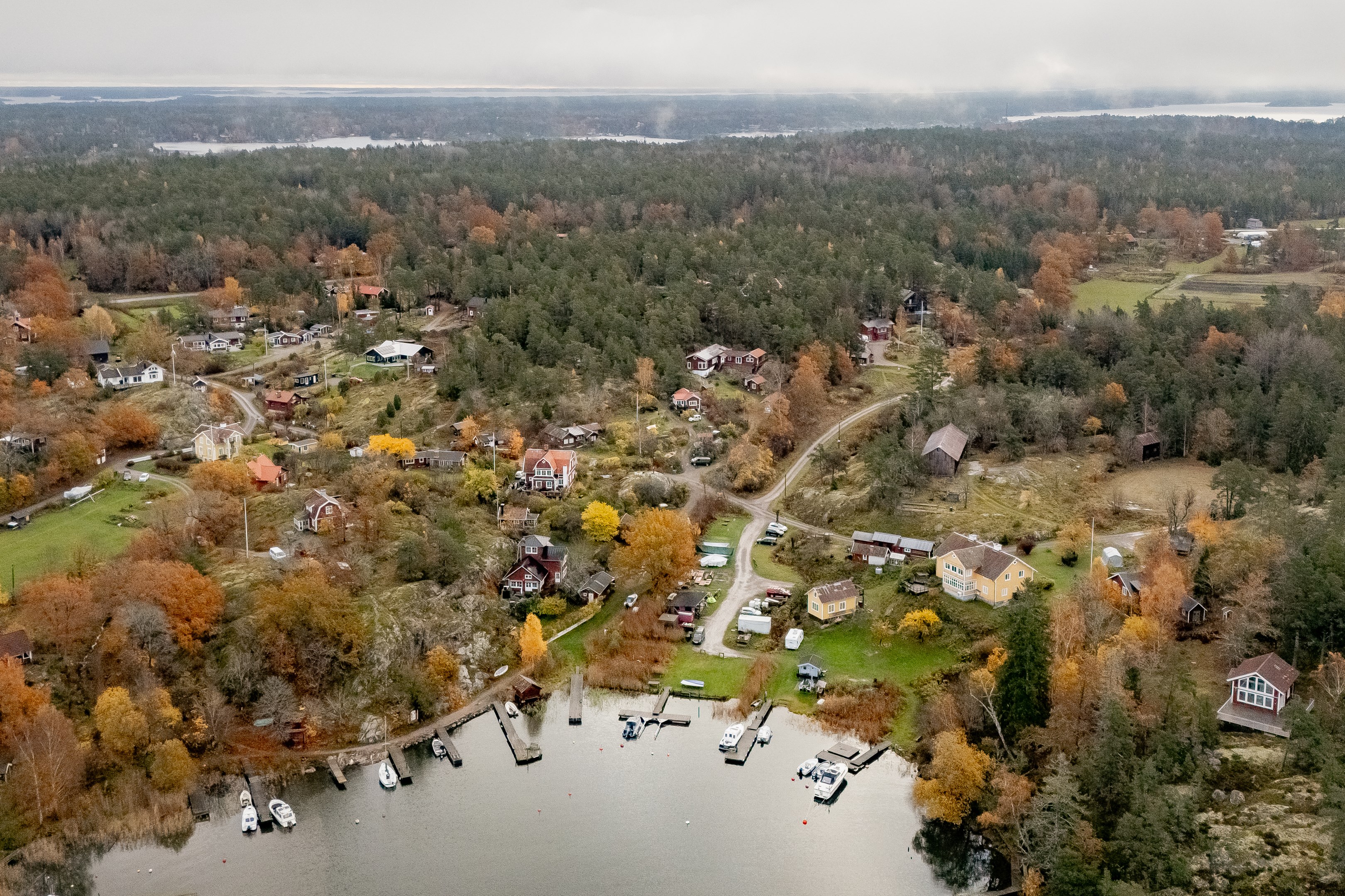 Vy över Hemviken - tomten skymtar utmed vägen mitt i bild.