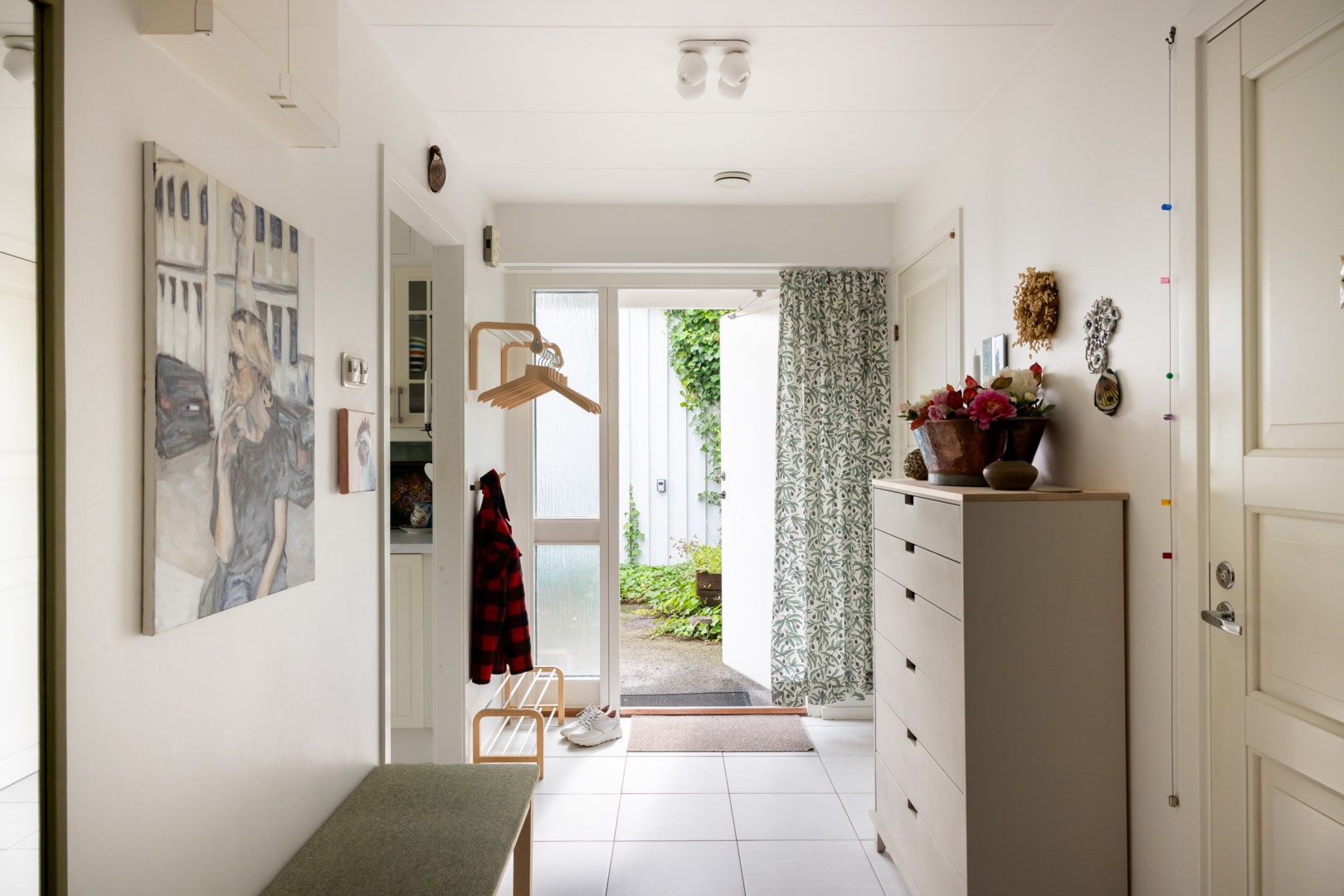 Välkomnande entréhall med praktisk klinkergolv som löper vidare in i köket