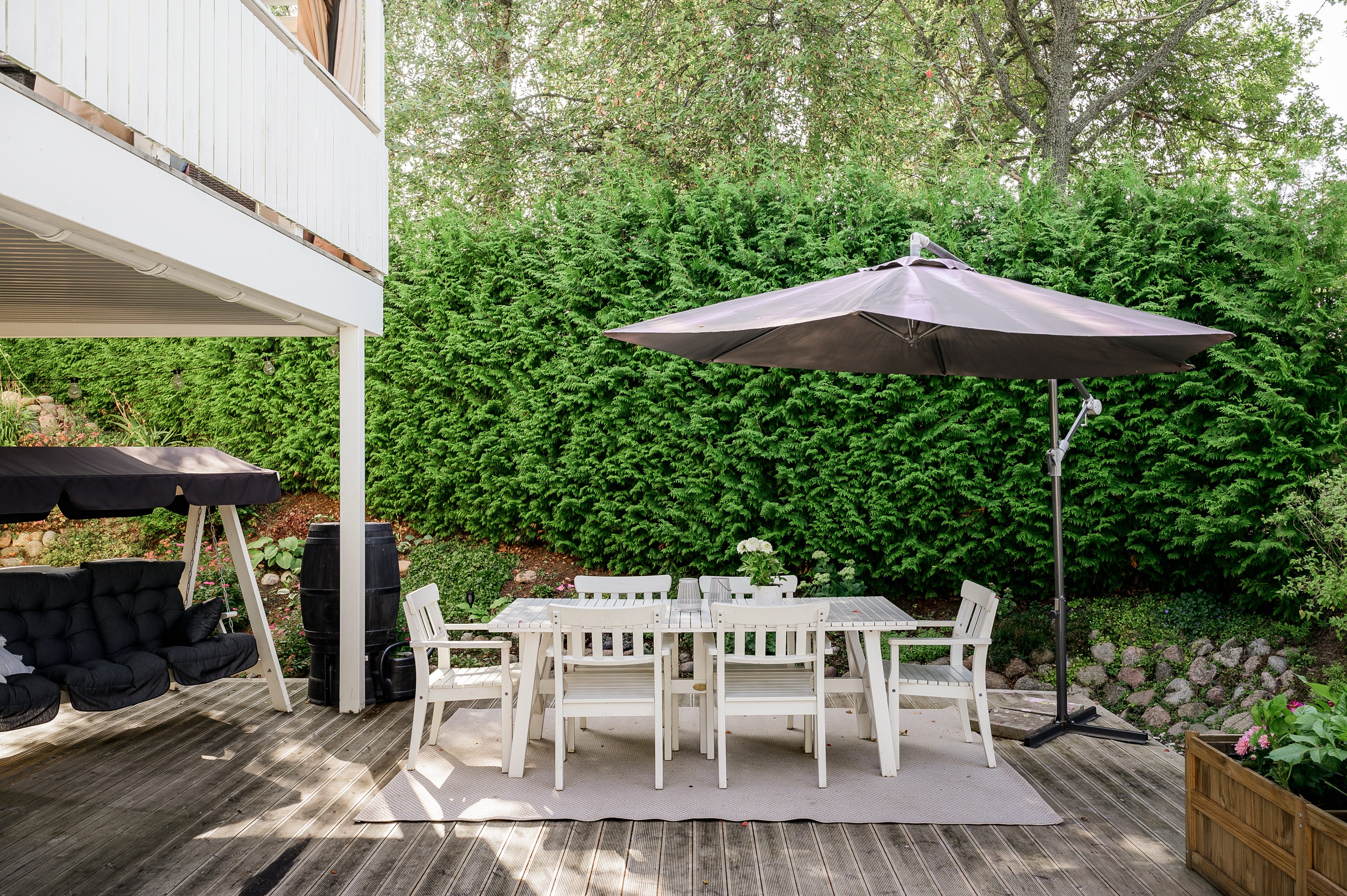 I söder ramas altan och trädgård ramas in av uppvuxen grönska.