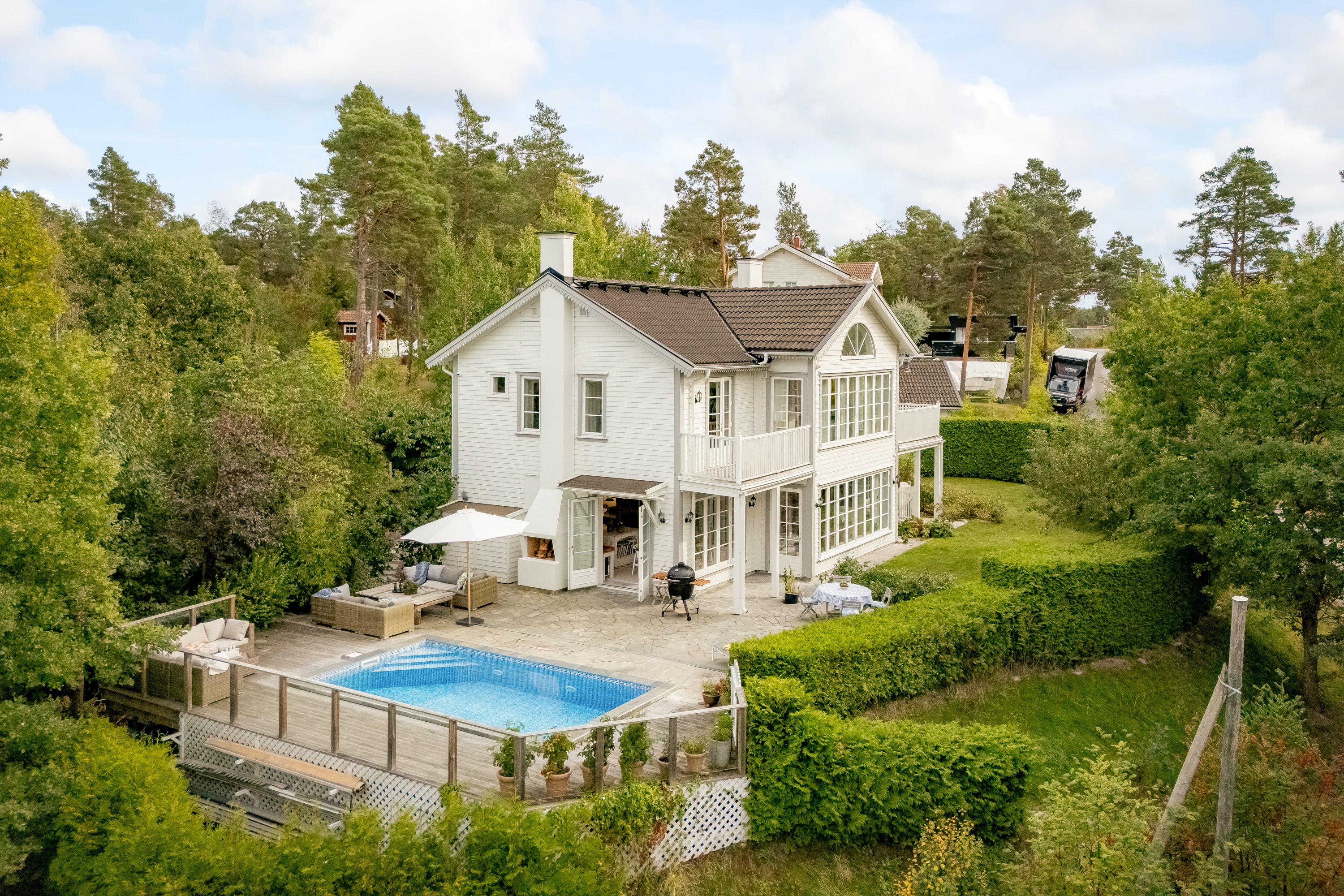 Poolområde med solsäkert sydvästläge inramad av uppvuxen grönska.