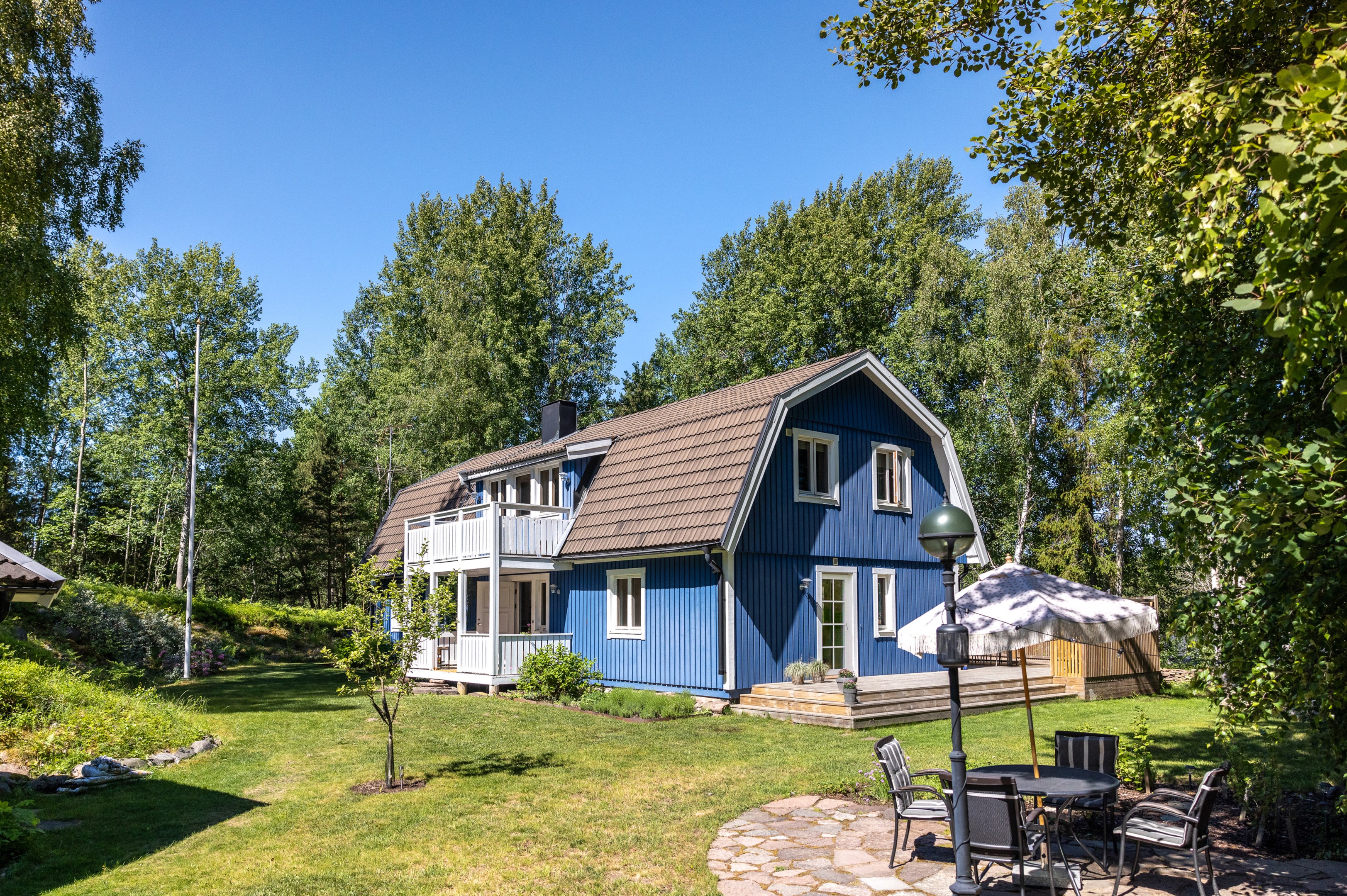 Huset och trädgård i vinkel från infarten