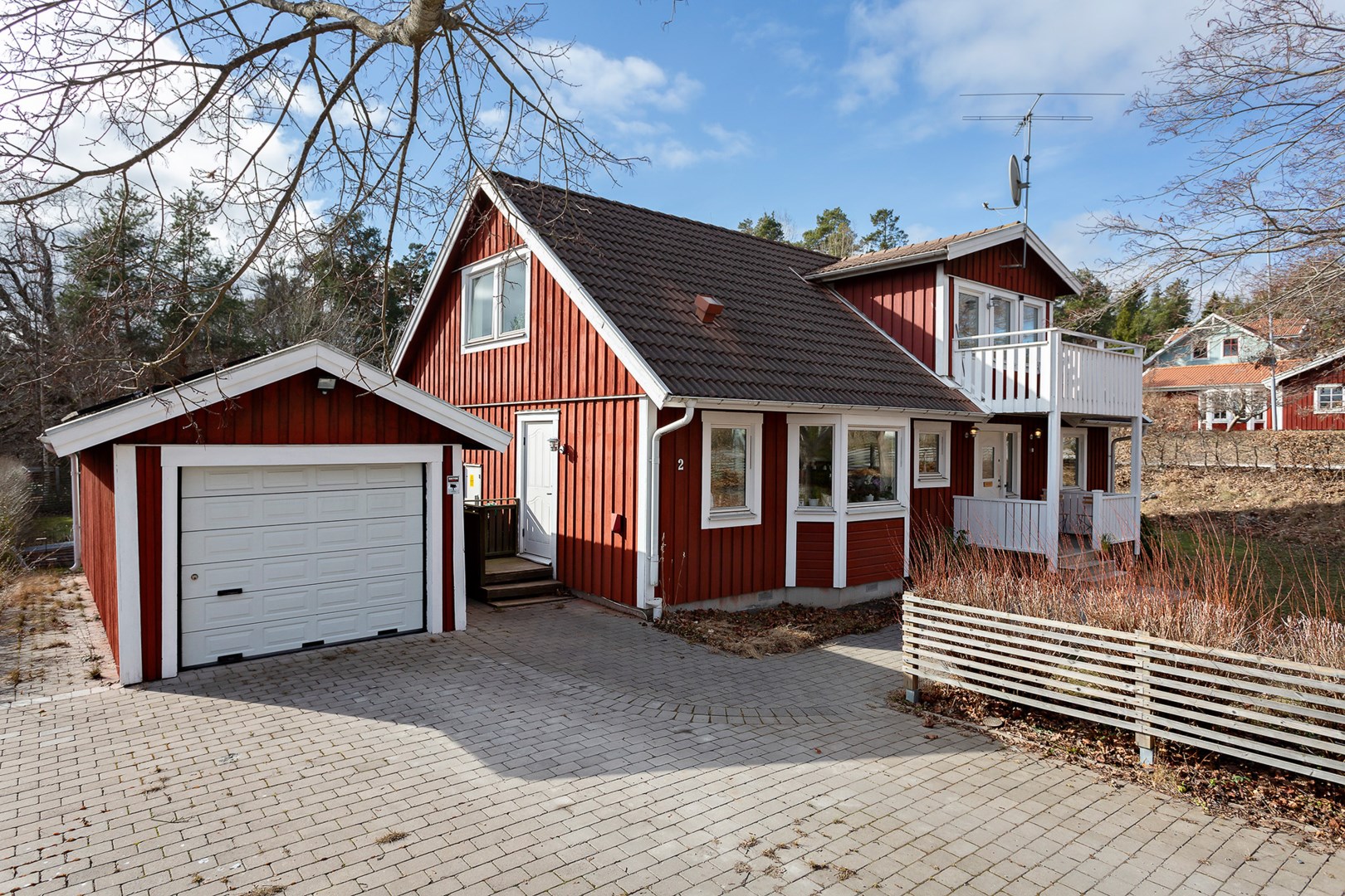 Stensatt parkering för flera bilar och isolerat garage med förråd