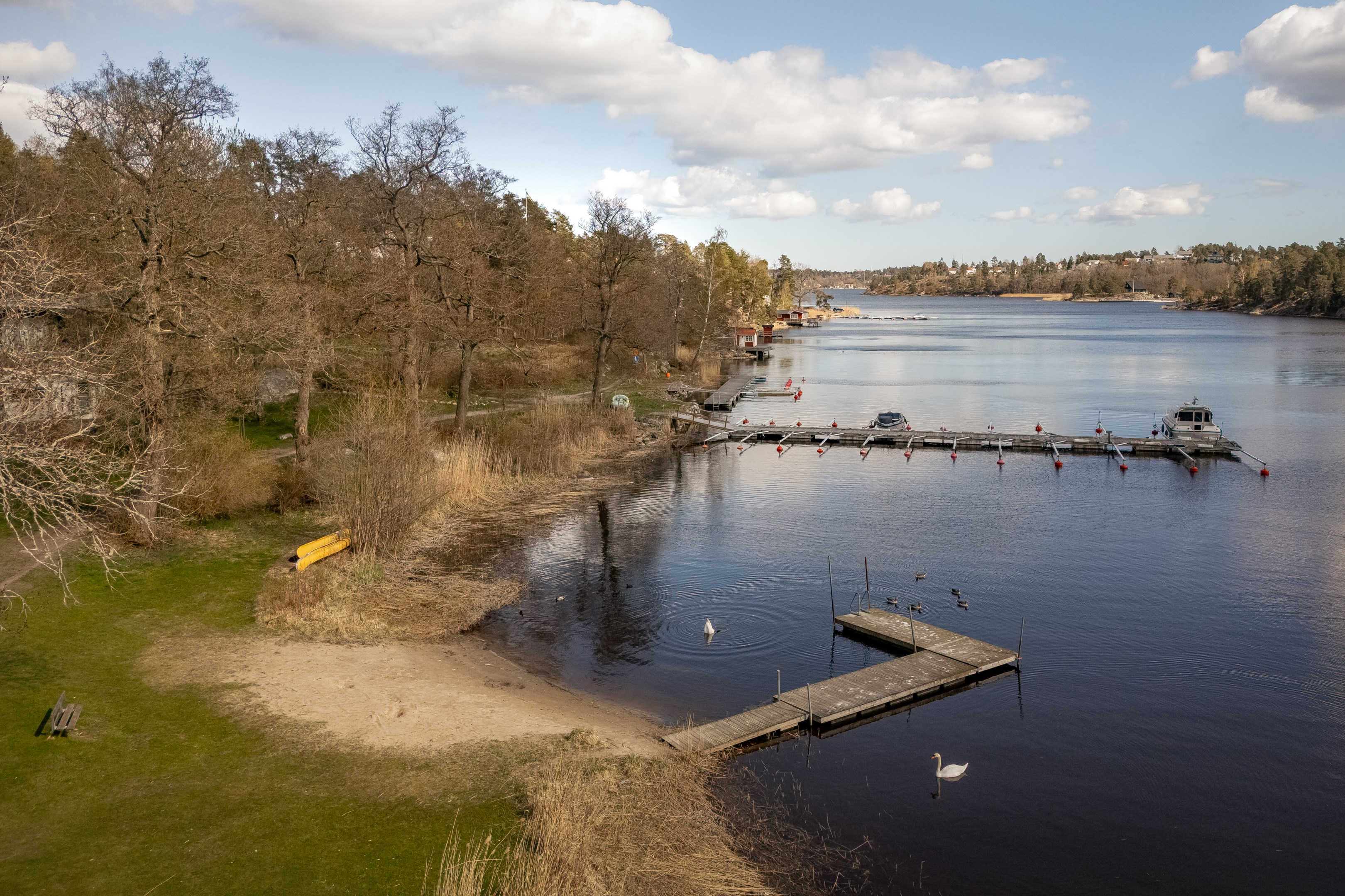 Badplats och brygga en bit in i viken - i anslutning finns en stor gräsplan där midsommarfirande hålls