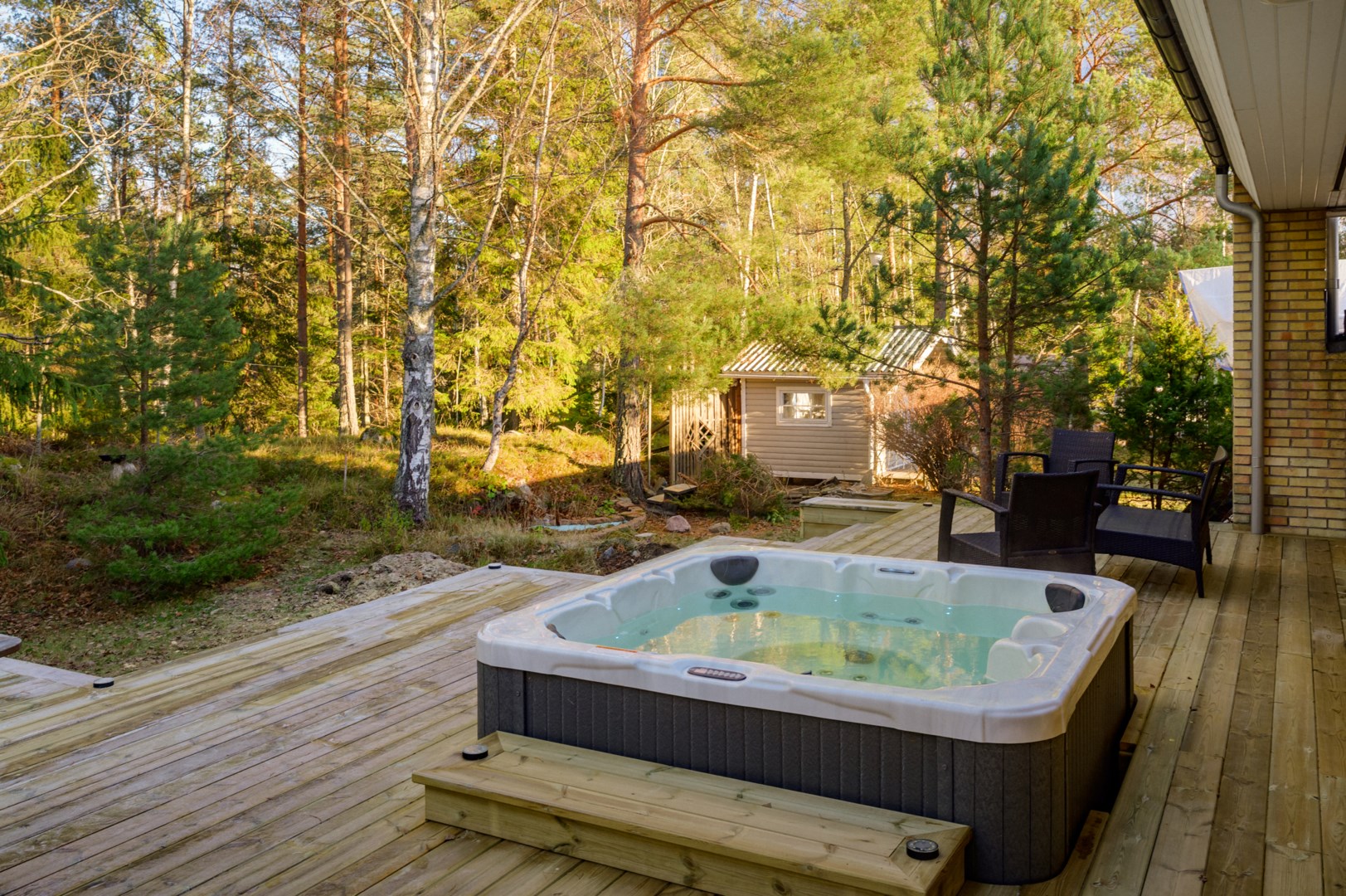 Altan med spabad och anslutande utekök och eldstad på husets baksida