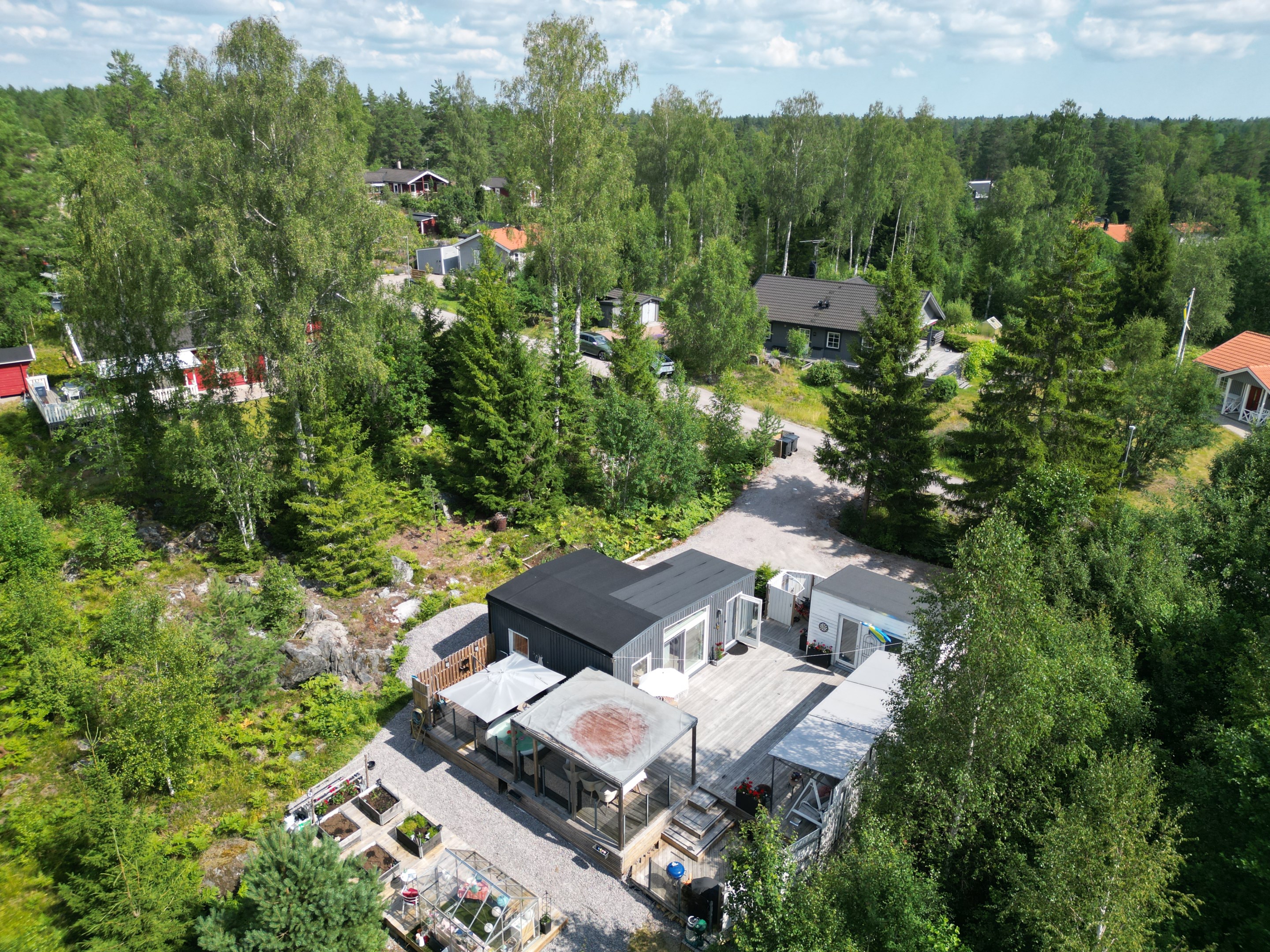 Fastigheten med två hus, altan, loggia, spabad, odlingslådor, växthus m.m.