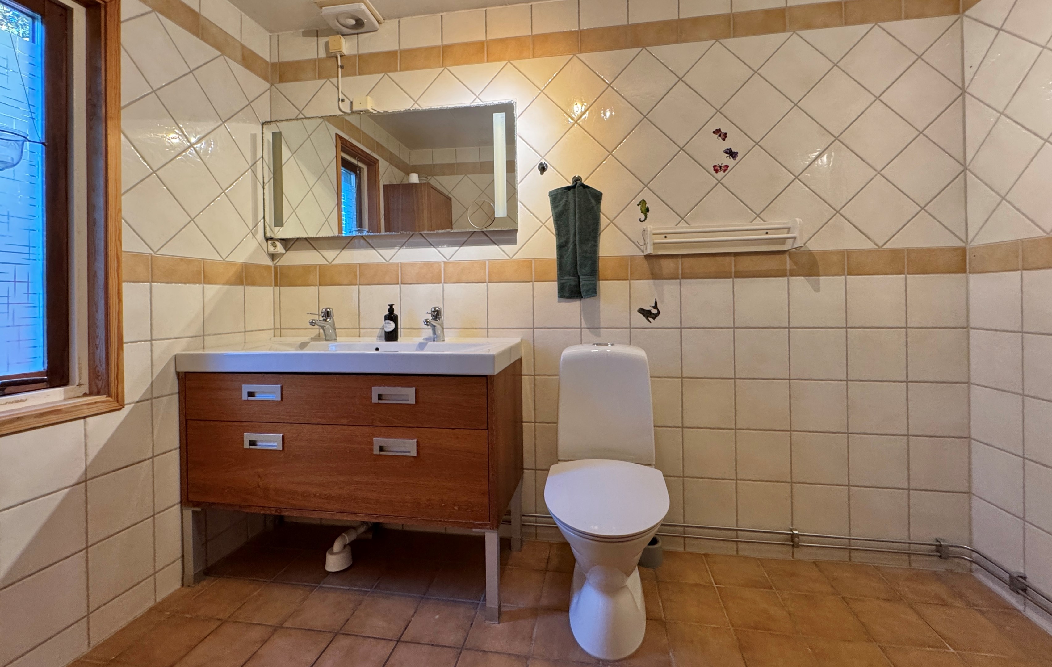 Badrum med kaklade väggar och klinkers på golvet