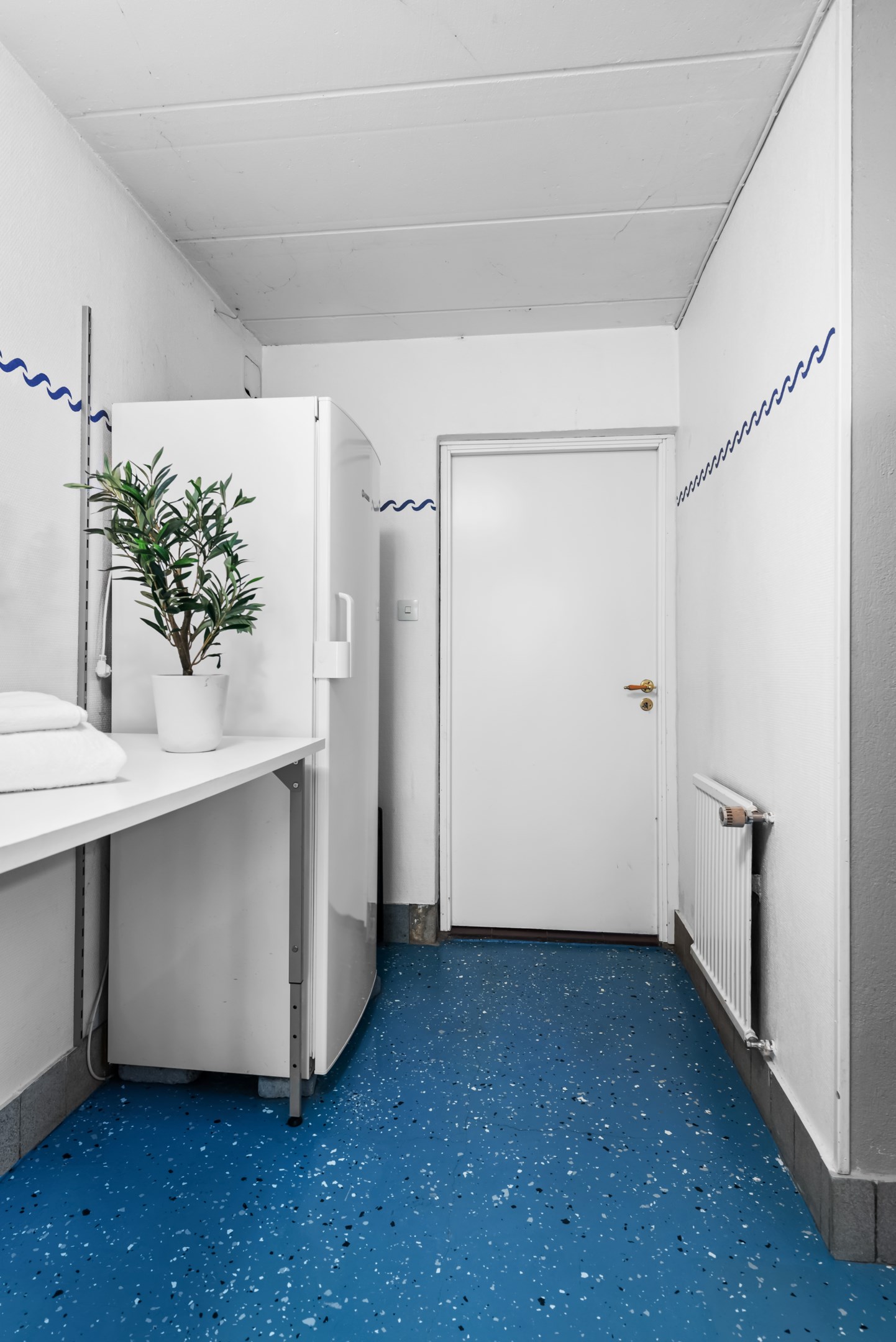 Tvättstuga i källaren med dörr mot verkstad