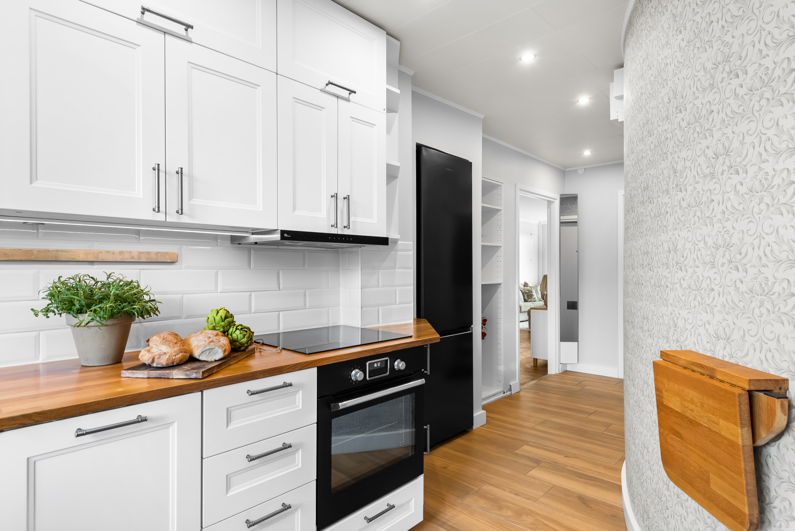 Kök med vy mot hall och vardagsrum till vänster