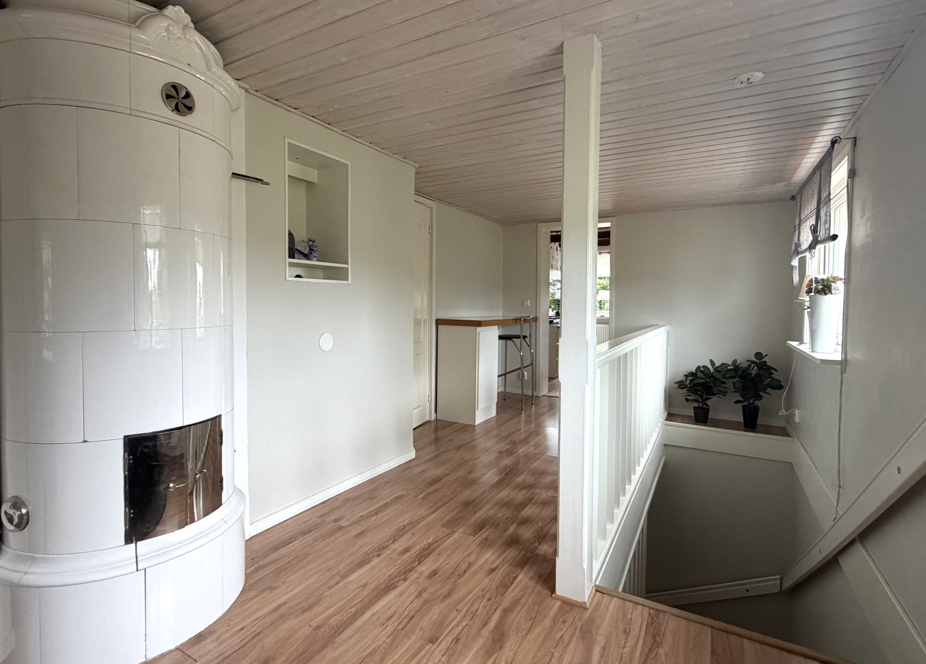 och kommer upp i en ljus, möblerbar hall med kamin och arbetsplats