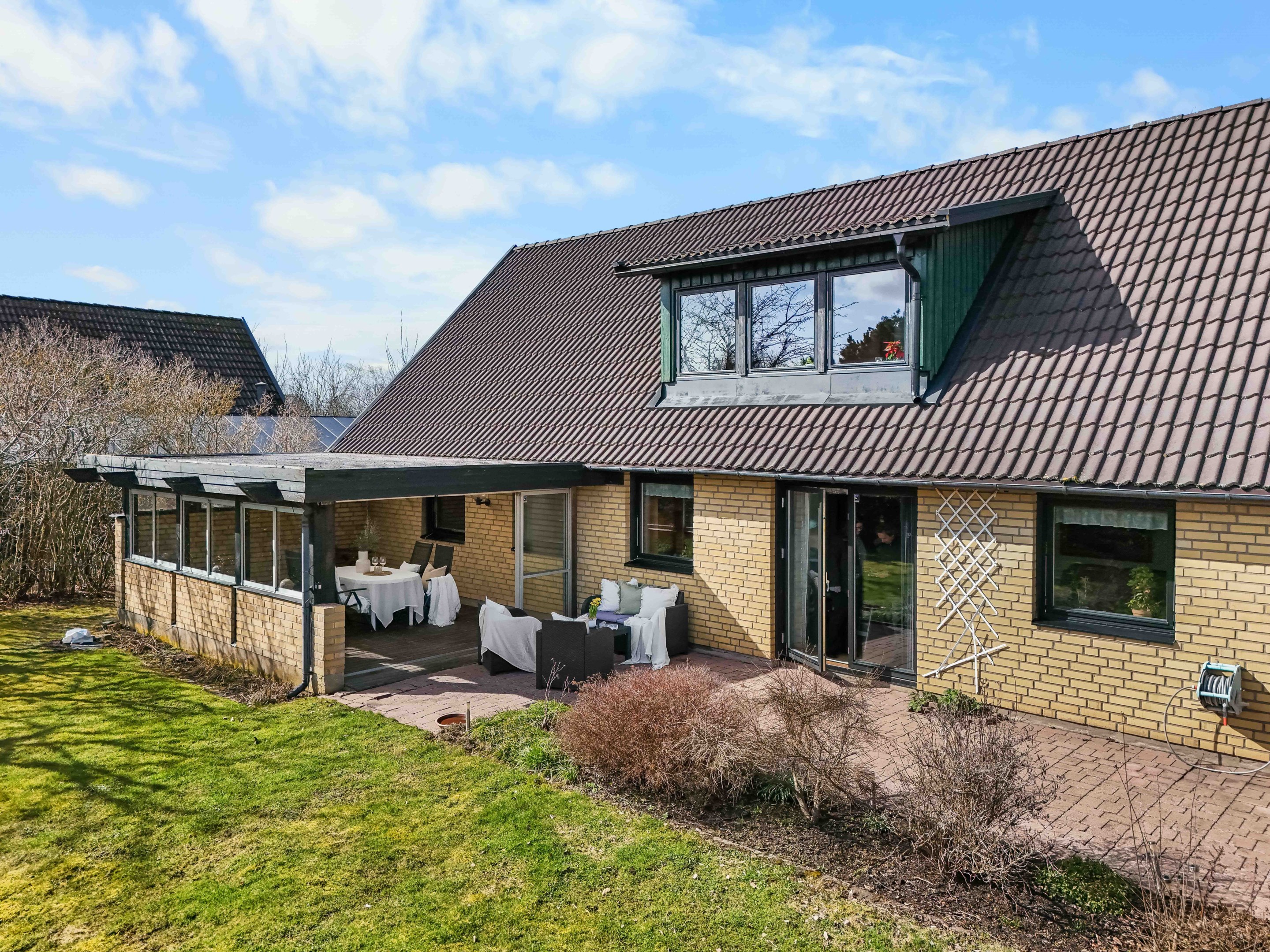 Husets baksida med uterum och härlig trädgård