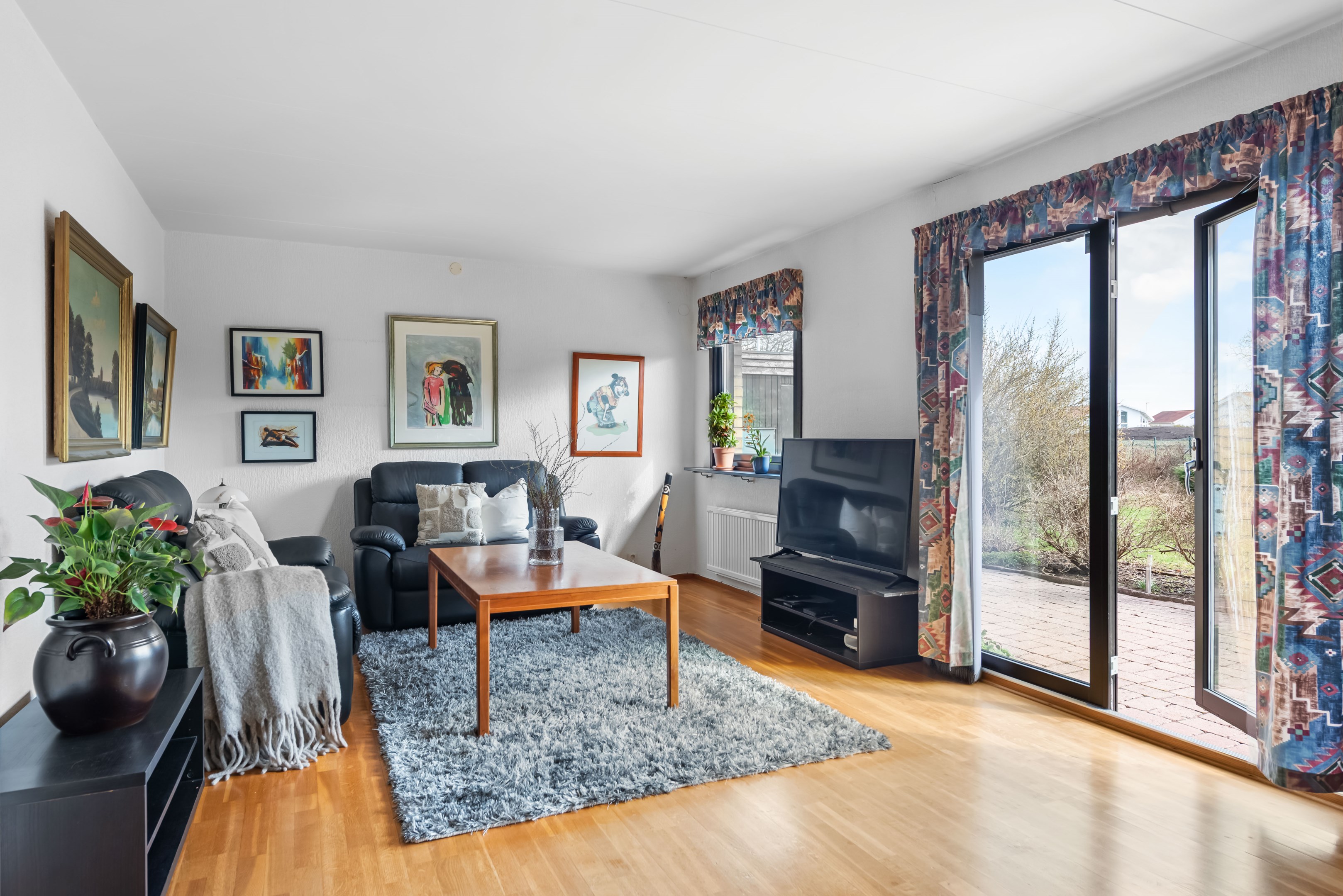 Fint vardagsrum med fönsterdörrar mot trädgården