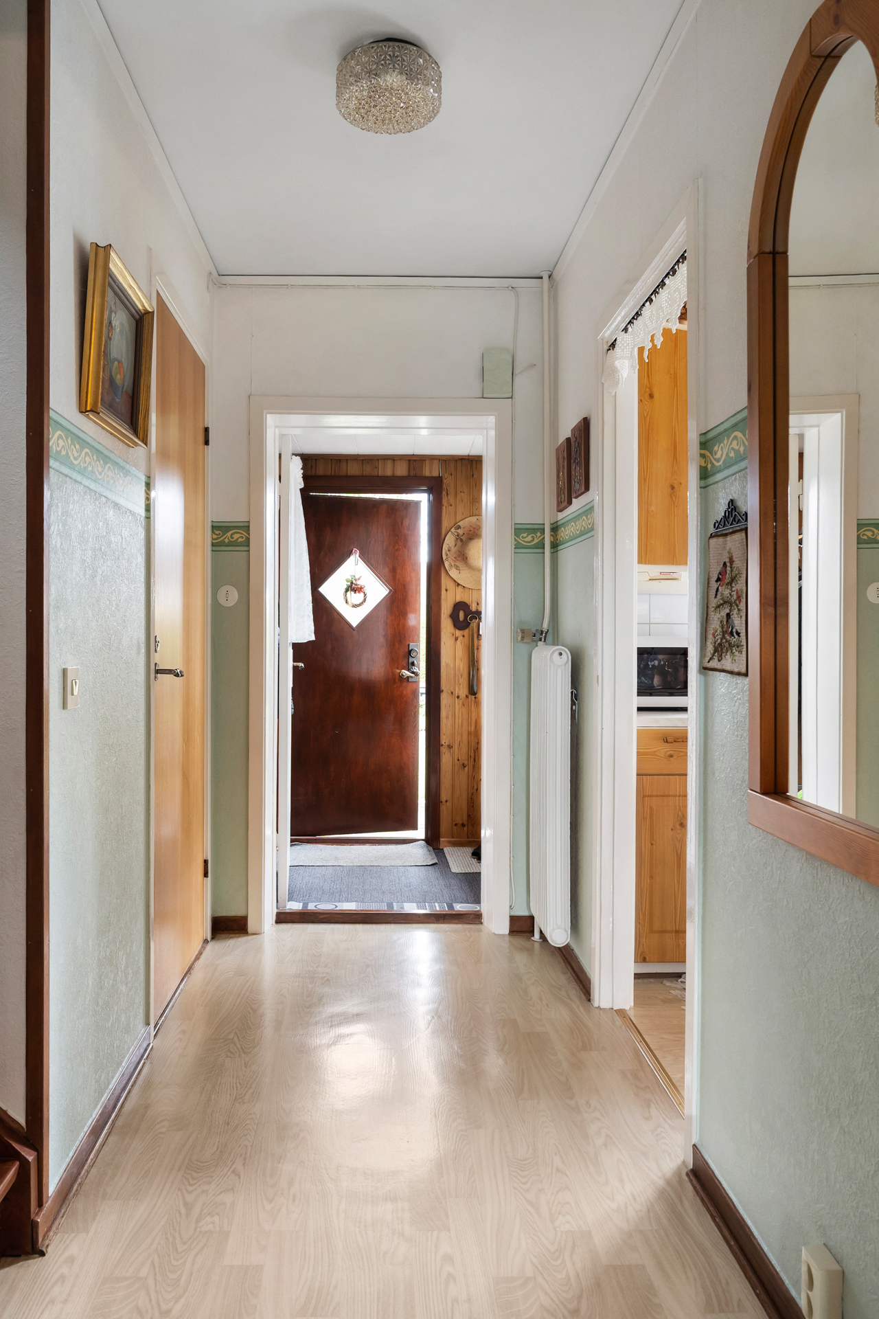 Hall med vy mot kök till höger och badrum och trappa till vänster