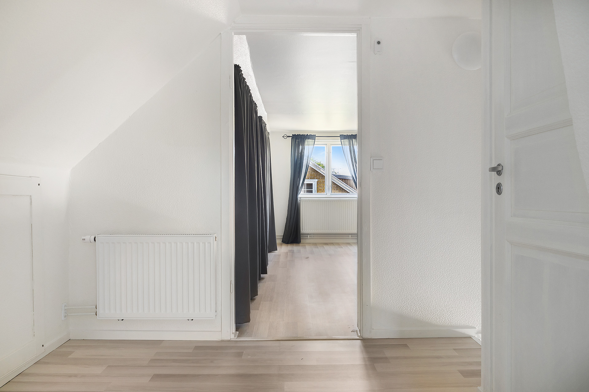 Hall ovanvåning med vy mot allrum. WC till höger